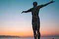 Closeup of Eliza sculpture silhouette at sunset over a seascape, purple and clear sky background