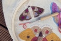 Closeup of embroidered butterflies on two-thread cloth in a hoop with punch needle and brick-red thread inside of it. Punch needle