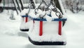 Closeup of empty chain swings on public playground at park being covered with snow during snowfall. Concept of winter holidays, Royalty Free Stock Photo