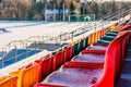 Closeup of Empty Colorful Football & x28;Soccer& x29; Stadium Seats in the Winter Covered in Snow - Sunny Winter Day