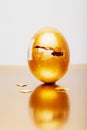 Golden egg with triangle hole placed on reflective table