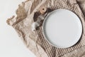 Closeup of empty porcelain plate mockup scene. Lifestyle composition with silk ribbon and dishware on brown craft paper Royalty Free Stock Photo