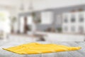 Closeup of a empty yellow striped tablecloth or napkin on a bright rustic wooden table against abstract blurred kittchen