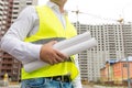 Closeup of engineer holding rolled blueprints in background of b Royalty Free Stock Photo