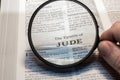 closeup of The epistle of Jude from Bible using a magnifying glass to enlarge print.