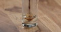 Closeup espresso pour into glass with cold water on wood table