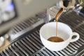 Closeup espresso pouring to white cup from coffee machine, selec