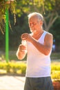 Grey Bearded Old Man in Vest Holds Water Bottle in Park Royalty Free Stock Photo