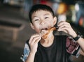 Closeup excited asian boy eating chicken leg Royalty Free Stock Photo