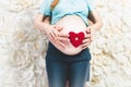 Closeup of expectant parents holding red hearth on stomach Royalty Free Stock Photo