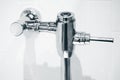 Closeup Exposed Manual Water Closet Flushometer. Flush Valve for Toilets Flushing System Dual Flow Type