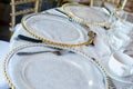 Closeup of exquisite table setting, transparent plates with golden framing Royalty Free Stock Photo