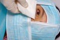 Closeup eye of woman peeking out from total facial cover, preparing for cosmetic surgery concept, doctor wiping with Royalty Free Stock Photo