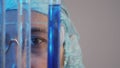 Closeup of eyes observing the diffusion of dissimilar liquids in test tubes in the foreground. The man works in the