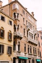 Closeup of the facade of a building, on the streets of Venice, Italy. Five-story stone building with white balconies Royalty Free Stock Photo