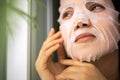 Closeup face beautiful young woman applying tissue moisturizing cooling facial mask for skin