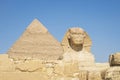 A closeup of the face of the Great Sphinx with pyramid in the background on a beautiful blue sky day in Giza, Cairo, Egypt. copy