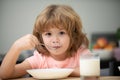 Closeup face of kid eating organic food, yogurt, milk. Child healthy eat. Smiling little boy eating food on kitchen. Royalty Free Stock Photo