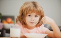 Closeup face of kid eating organic food, yogurt, milk. Child healthy eat. Smiling little boy eating food on kitchen. Royalty Free Stock Photo