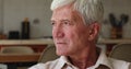 Closeup face serious grey-haired man sit indoor staring into distance