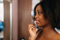 Closeup face of smiling African young woman using cosmetics brush, looking to mirror. Beautiful black female putting Royalty Free Stock Photo