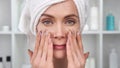 Closeup face of smiling woman applying cream on skin. Shot with RED camera in 4K