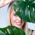 Closeup facial portrait personable woman holding green monstera.