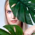 Closeup facial portrait personable woman holding green monstera.