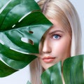 Closeup facial portrait personable woman holding green monstera.