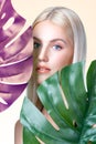 Closeup facial portrait personable woman holding green monstera.