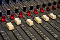 Closeup of faders on a large studio audio mixing board.