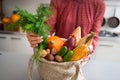 Closeup of fall vegetables and nuts in burlap bag held by woman