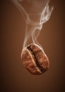 Closeup falling coffee bean with smoke on brown background