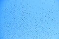 Closeup of falling water droplets on blue background. Royalty Free Stock Photo