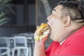 Closeup of fat Asian man gaping a cheeseburger