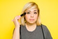 Closeup of a fat woman with dyed hair putting on some makeup with a brush and making eye contact Royalty Free Stock Photo