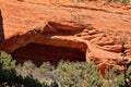 Closeup of Fay Canyon Arch, in the Red Rocks of Sedona, Arizona. Green juniper are growing in the foreground. Royalty Free Stock Photo