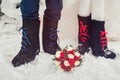 A closeup of the feet of the bride and groom in felt boots on snow wedding bouquet. Accessories for a stylized Russian wedding