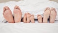 Closeup of feet of family lying in bed. Bare feet of parents and children sticking out in bed. Family with two children Royalty Free Stock Photo