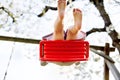 Closeup of feet of little toddler girl having fun on swing in domestic garden. Small child swinging under blooming trees Royalty Free Stock Photo