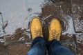 Feet of man wearing leather boots standing in a puddle of water in the street Royalty Free Stock Photo