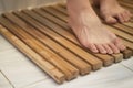 closeup of feet stepping on a wooden sauna mat