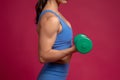 Closeup of female arm with dumbbell on maroon background Royalty Free Stock Photo