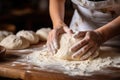 closeup of a female chef\'s hands making dough on a wooden table