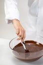 Closeup female chef stirring dark melted chocolate isolated on white background