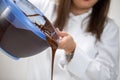 Closeup chocolatier pouring out of bowl dark melted hand-crafted chocolate