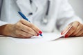 Closeup of a female doctor hands with a blue pen making notes and filling in diagnosis of patient on a paper. Coronavirus test and
