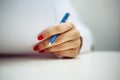 Closeup of a female doctor hands with a blue pen making notes and filling in diagnosis of patient on a paper. Coronavirus test and