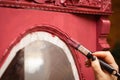 Closeup of female hand aging handmade ornaments of old wooden cupboard door in pink color. Giving new life to old stuff