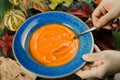 Closeup of a female hand holding a blue ceramic plate with pumpkin soup and spoon Royalty Free Stock Photo